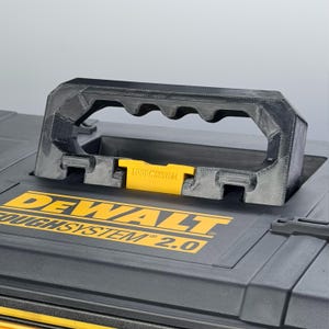 May include: Black and yellow DEWALT TOUGH SYSTEM 2.0 toolbox with a textured black handle. The handle is designed for easy carrying. The toolbox has a yellow latch and the DEWALT logo in yellow.
