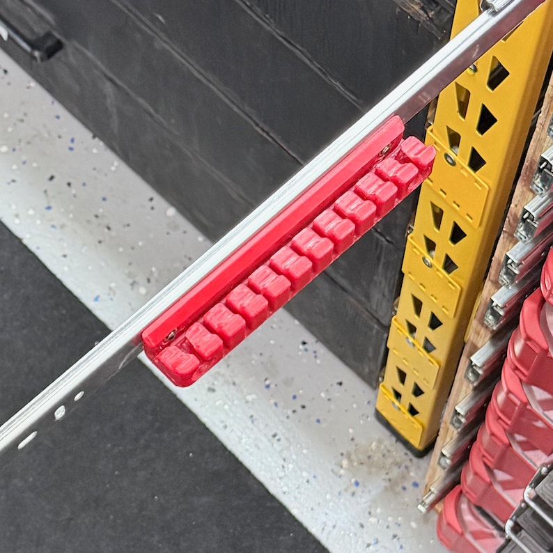K&ouml;nnte beinhalten: Eine rote Steckschl&uuml;ssel-Organizerschiene aus Kunststoff mit zehn einzelnen Steckpl&auml;tzen zur Aufnahme von Steckschl&uuml;sseln, die sicher an einer silbernen Metall-Schubladenschiene befestigt ist. Die Basis hat erh&ouml;hte Trennw&auml;nde.