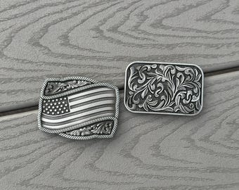 May include: Two silver belt buckles, one with a floral design and the other with an American flag design.