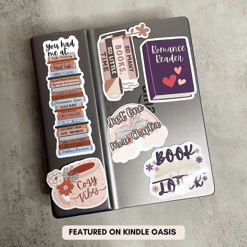 Op de afbeelding: Een set van 7 boek-thema stickers met een stapel boeken met de tekst "So Many Books, So Little Time", een paars boek met de tekst "Romance Reader", een boek met de tekst "Just One More Chapter", een mok met de tekst "Cozy Vibes", een boek met de tekst "Book Lover", en de tekst "You had me at... Fake Dating" op een stapel boeken.