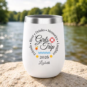 Pode incluir: Um copo branco de aço inoxidável com borda prateada apresentando o texto Girls Trip, Friends, River, Drinks, Memories, Laughter, 2026 e o nome Lizbeth, acompanhado por ícones de uma boia salva-vidas, um coquetel, ondas e dois sóis.