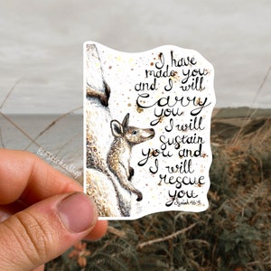 May include: A sticker featuring a watercolor illustration of a kangaroo mother carrying her joey in her pouch. The sticker has a white background with gold glitter accents and the text "I have made you and I will carry you. I will sustain you and I will rescue you. Isaiah 46:4."