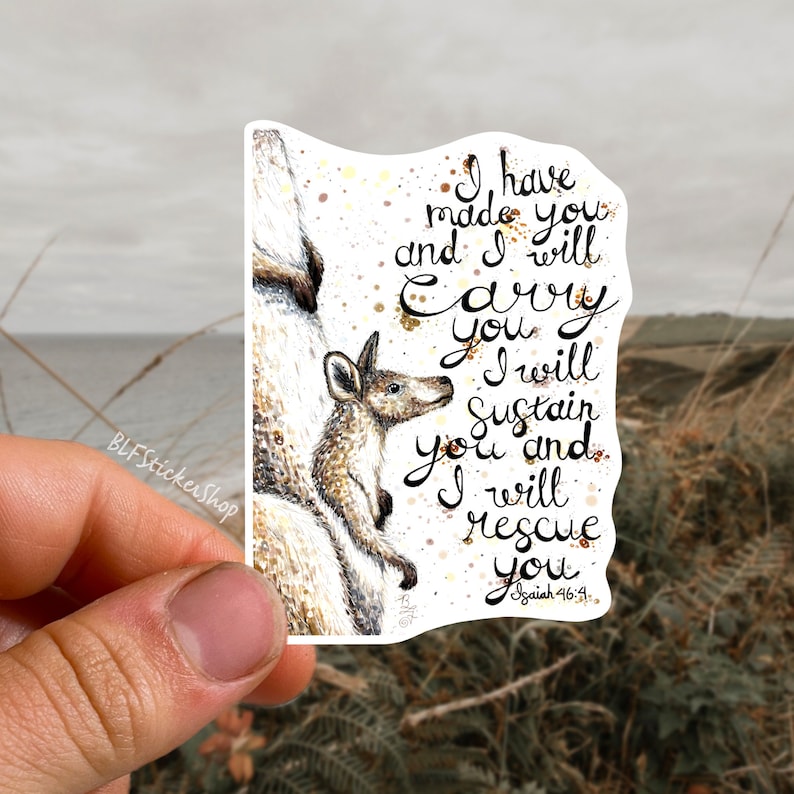 May include: A sticker featuring a watercolor illustration of a kangaroo mother carrying her joey in her pouch. The sticker has a white background with gold glitter accents and the text "I have made you and I will carry you. I will sustain you and I will rescue you. Isaiah 46:4."