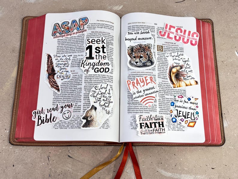 以下が含まれることがあります： 赤い縁と茶色の表紙が付いた開いた聖書で、宗教的なフレーズとイラストが描かれたステッカーが付いています。「ASAP」、「1st the Kingdom of God」、「Prayer」、「Jesus」という言葉が含まれています。