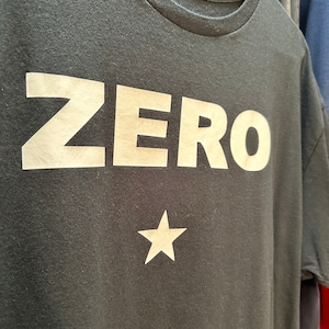 May include: A black t-shirt with the word "ZERO" printed in white on the front. A white star is below the word.
