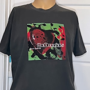 May include: A black t-shirt with a graphic print of the album cover for "Last Splash" by The Breeders. The album cover features a red heart with a green and black background.