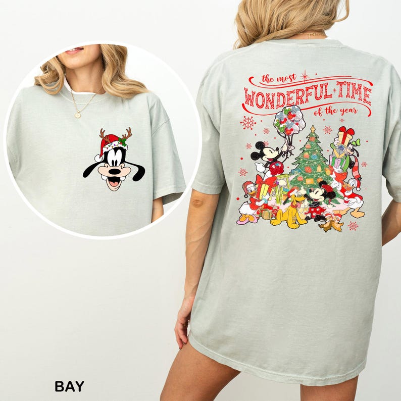 Puede incluir: Una camiseta verde claro con un dise&ntilde;o navide&ntilde;o con Mickey Mouse, Minnie Mouse, Goofy, Donald Duck y Pluto. El texto en la parte posterior de la camiseta dice "the most WONDERFUL TIME of the year".