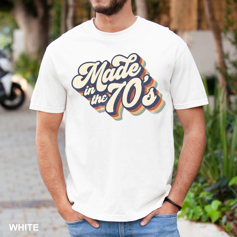 Puede incluir: Una camiseta blanca con un gr&aacute;fico de estilo retro que dice "Made in the 70's" en texto colorido y superpuesto.