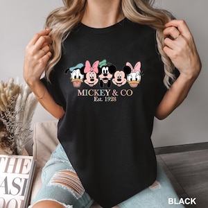 May include: Black t-shirt with a graphic of Mickey Mouse and friends. The text "MICKEY & CO Est. 1928" is printed below the graphic.