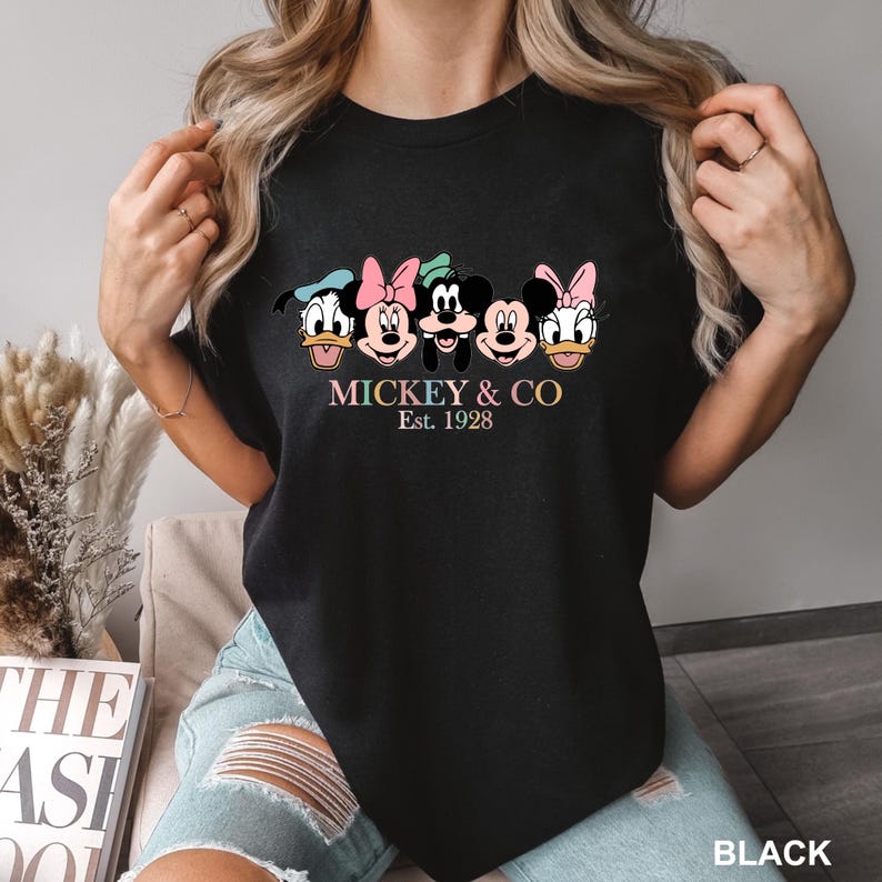 May include: Black t-shirt with a graphic of Mickey Mouse and friends. The text "MICKEY & CO Est. 1928" is printed below the graphic.