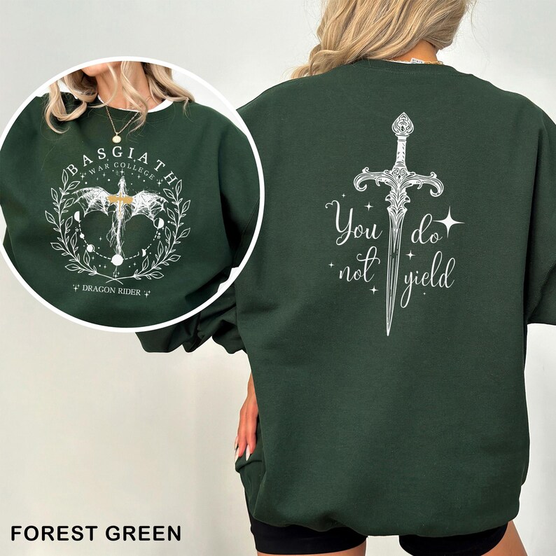 May include: Forest green sweatshirt with white graphic designs. The front features a circular design with text that reads "BASGIATH WAR COLLEGE" and "DRAGON RIDER". The back displays a sword design with the words "You do not yield".