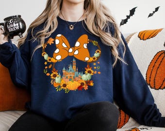 May include: A navy blue sweatshirt with a white and orange bow with white polka dots, a fall-themed castle, and the text "Witch's Brew" on a black mug.
