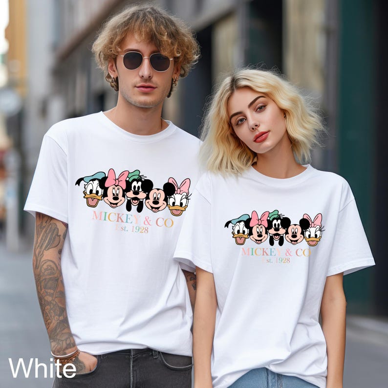 May include: Two white t-shirts with a graphic print of Mickey Mouse and friends. The text on the shirts reads "Mickey & Co. Est. 1928".