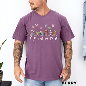 May include: Berry-coloured t-shirt with the word "FRIENDS" in white, featuring cartoon characters and Mickey Mouse balloons. The shirt has a crew neck and short sleeves.