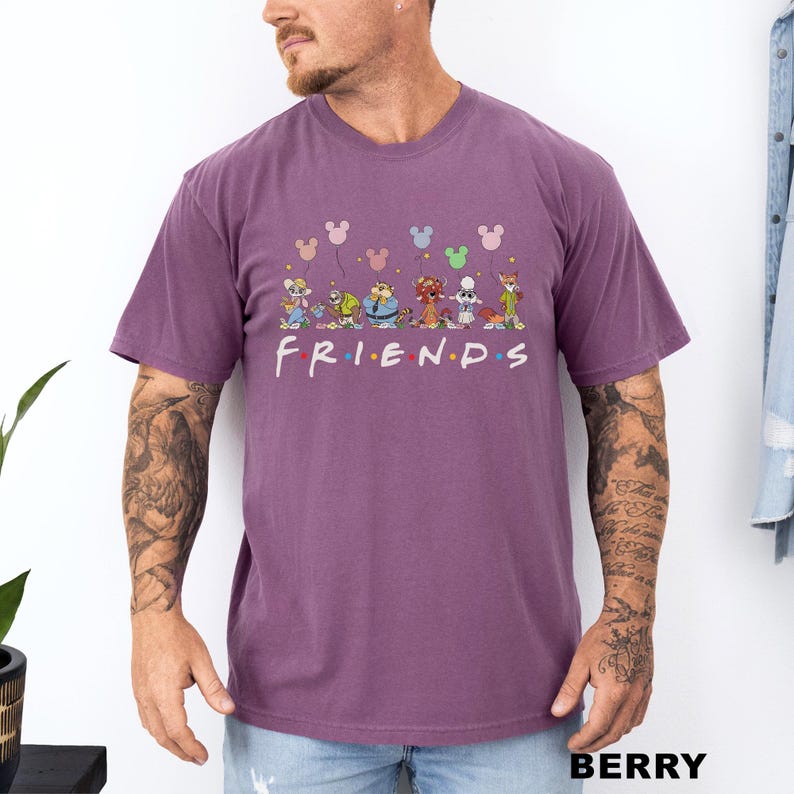 May include: Berry-coloured t-shirt with the word "FRIENDS" in white, featuring cartoon characters and Mickey Mouse balloons. The shirt has a crew neck and short sleeves.