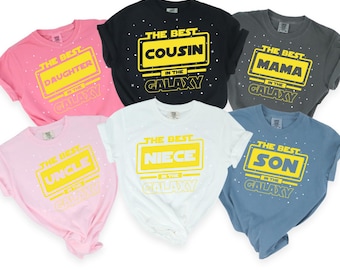 May include: Six t-shirts with a Star Wars themed design. The shirts are in different colors and feature the text "The Best" with a different family member title in each shirt. The titles are "Daughter", "Cousin", "Mama", "Uncle", "Niece", and "Son".