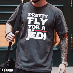 May include: A dark gray t-shirt with a white graphic that says "Pretty Fly For A Jedi" with a red lightsaber graphic.