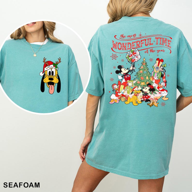 Puede incluir: Una camiseta azul turquesa con un dise&ntilde;o navide&ntilde;o con Mickey Mouse y sus amigos. La parte posterior de la camiseta dice "The most wonderful time of the year".