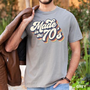 Puede incluir: Una camiseta gris con un gr&aacute;fico de estilo retro que dice "Made in the 70's".