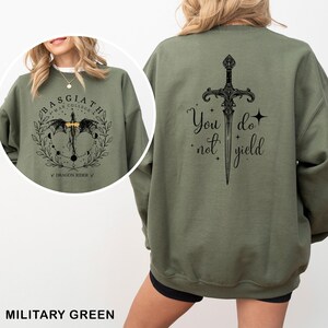 May include: Military green sweatshirt with a graphic on the front that says "Basgiath War College Dragon Rider" and a sword design on the back with the text "You do not yield".
