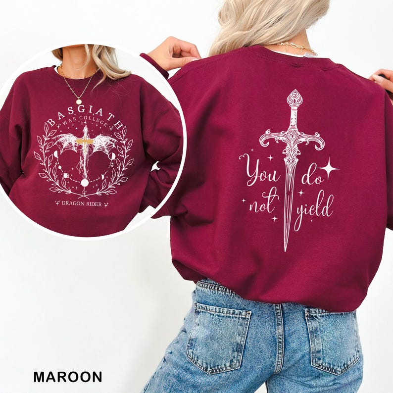 May include: Maroon sweatshirt with white graphic designs. The front features a circular design with text and a winged creature. The back displays a sword graphic with the words "You do not yield".