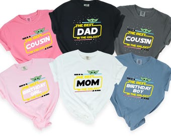 May include: Six t-shirts with different designs featuring a green alien character and the text "The Best" followed by a title like "Dad", "Mom", "Cousin", "Birthday Girl", "Birthday Boy" and the words "in the galaxy".