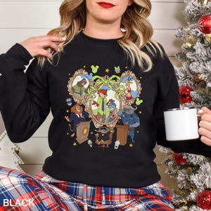 May include: Black crewneck sweatshirt featuring a colorful cartoon illustration of animal characters in a decorative frame. The design includes a lion, fox, bunny, and other characters. The word "BLACK" is printed at the bottom.