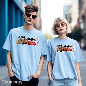 May include: Two light blue t-shirts with a graphic print of the characters Lightning McQueen and Mater from the Disney Pixar movie Cars. The graphic also includes Mickey Mouse ears and other details.