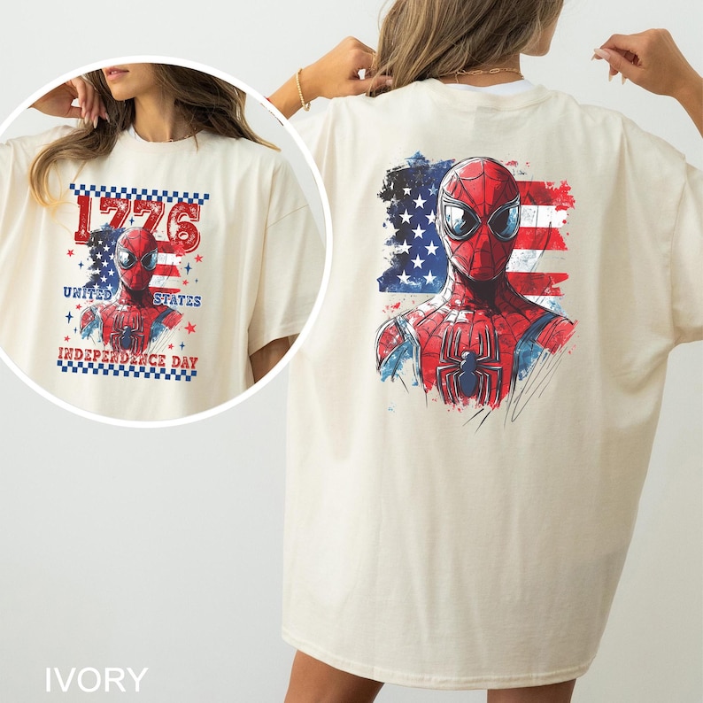 May include: An ivory t-shirt featuring a graphic of a red and blue superhero mask and suit against a distressed American flag background. A circular inset shows the same graphic with the text 1776 UNITED STATES INDEPENDENCE DAY.
