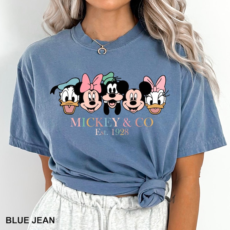 May include: A blue t-shirt with a graphic of Mickey Mouse and friends. The text "Mickey & Co. Est. 1928" is printed below the graphic.