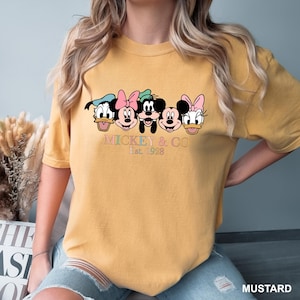May include: A mustard yellow t-shirt with a graphic of Mickey Mouse and friends. The text "Mickey & Co. Est. 1928" is printed below the graphic.