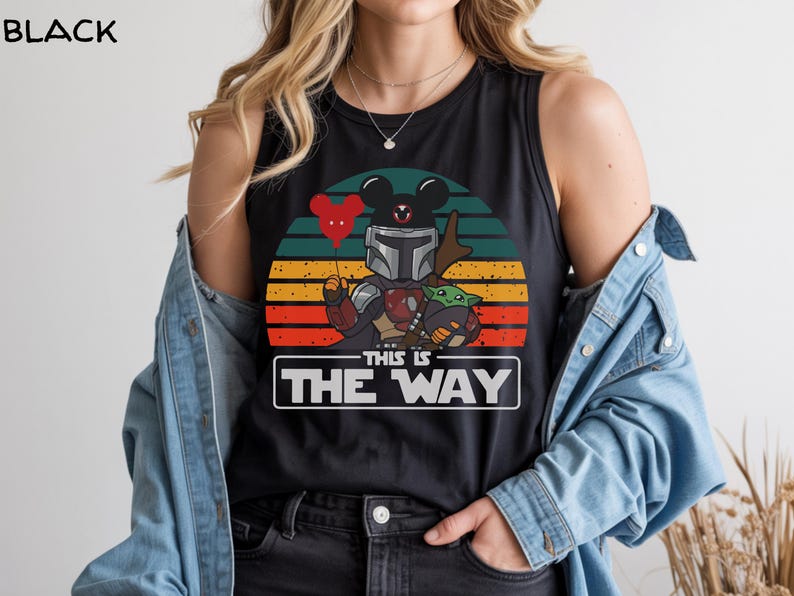 May include: Black tank top featuring a graphic of The Mandalorian and Grogu with a Mickey Mouse head balloon against a sunset backdrop. The text "THIS IS THE WAY" is displayed in a white rectangle.