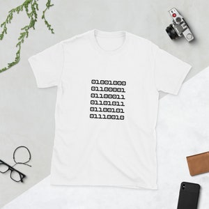 Könnte beinhalten: Weißes T-Shirt mit einem schwarzen Design aus einer Reihe von Binärcode-Zahlen: 0110011000, 011100001, 011100111, 011101011, 011100101, 011110010.