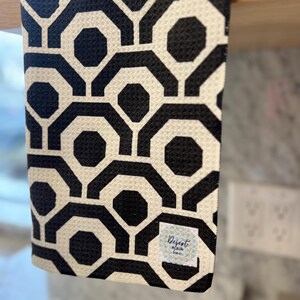 May include: Black and white geometric patterned kitchen towel with a small white label that says "Desert Aqua Home".
