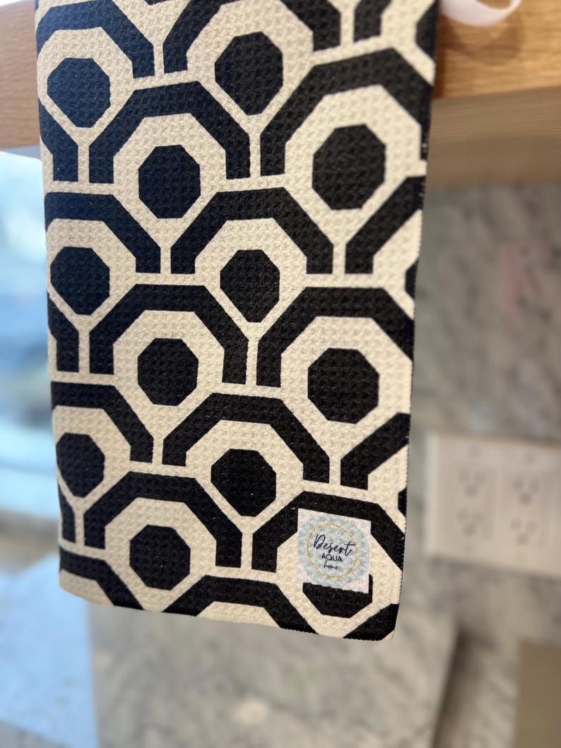 May include: Black and white geometric patterned kitchen towel with a small white label that says "Desert Aqua Home".
