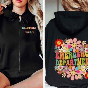 May include: Black zip-up hoodie with the text "CUSTOM TEXT" in colorful letters on the front. The back features a floral design with the words "EMERGENCY DEPARTMENT" in a retro font, surrounded by smiling flowers.