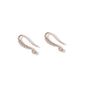 May include: Two rose gold earring hooks with a curved design. Each hook features a row of small, clear crystals along the curved portion. The hooks are designed for jewelry making and crafting.