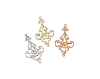 May include: Three ornate metal charms in gold, silver, and rose gold. Each charm features a floral design with a central flower and intricate scrollwork.