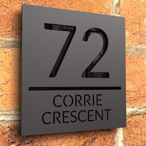 Peut inclure: Une plaque de numéro de maison noire avec le numéro 72 et le nom de la rue Corrie Crescent.