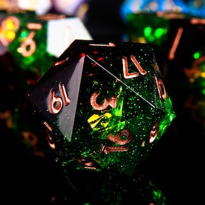 May include: A green and black d20 dice with copper numbers. The dice has a glittery finish and is made of resin.