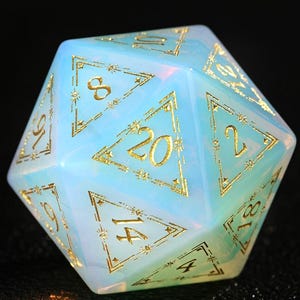 May include: A twenty-sided die with a pearlescent, opalescent finish. The die features gold-colored numerals and decorative accents. The numbers are clearly visible against the light blue and white background. This gaming accessory is perfect for tabletop games.