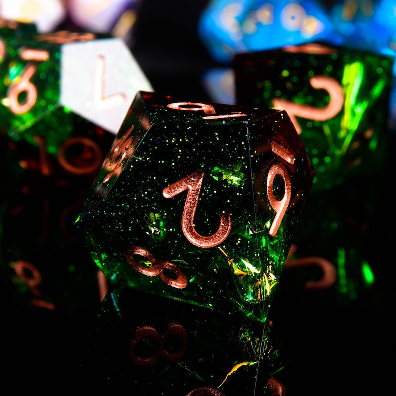 May include: Close-up of a green, glittery, multi-sided dice with copper-coloured numbers. The dice is sitting on a black surface.