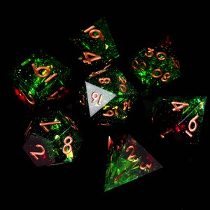 May include: A set of seven green and red dice with copper-coloured numbers. The dice are made of a translucent material with a glittery finish.