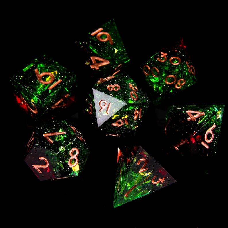 May include: A set of seven green and red dice with copper-coloured numbers. The dice are made of a translucent material with a glittery finish.