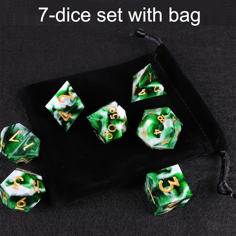 May include: A set of seven green and white dice with gold numbers, in a black velvet bag. The dice are marbled with green and white swirls. The bag has a drawstring closure.  7-dice set with bag.