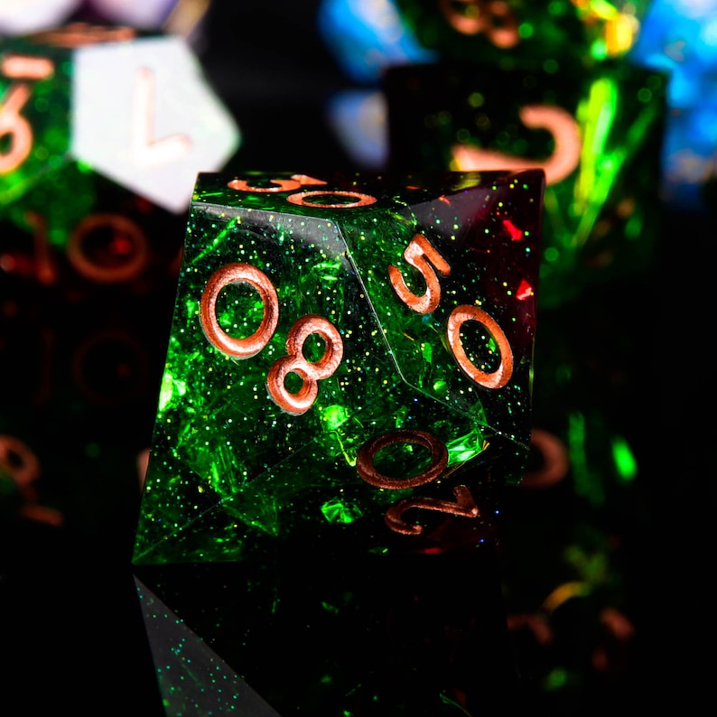 May include: A green and red iridescent d20 dice with copper-coloured numbers. The dice has a glittery finish.