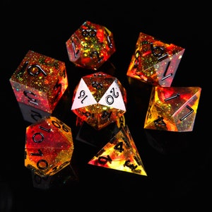 May include: Set of seven polyhedral dice with a red, orange, and yellow color scheme and a glittery finish. The dice are numbered 1-20.