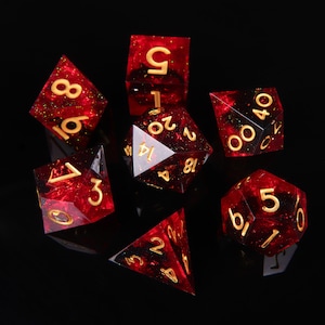 May include: Set of seven red and gold dice with black flecks. The dice are numbered 1 through 6 and 20. The dice are on a black background.