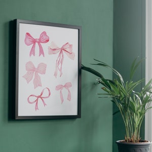 May include: A framed print with a white background featuring six pink watercolor bows of various sizes and shapes.
