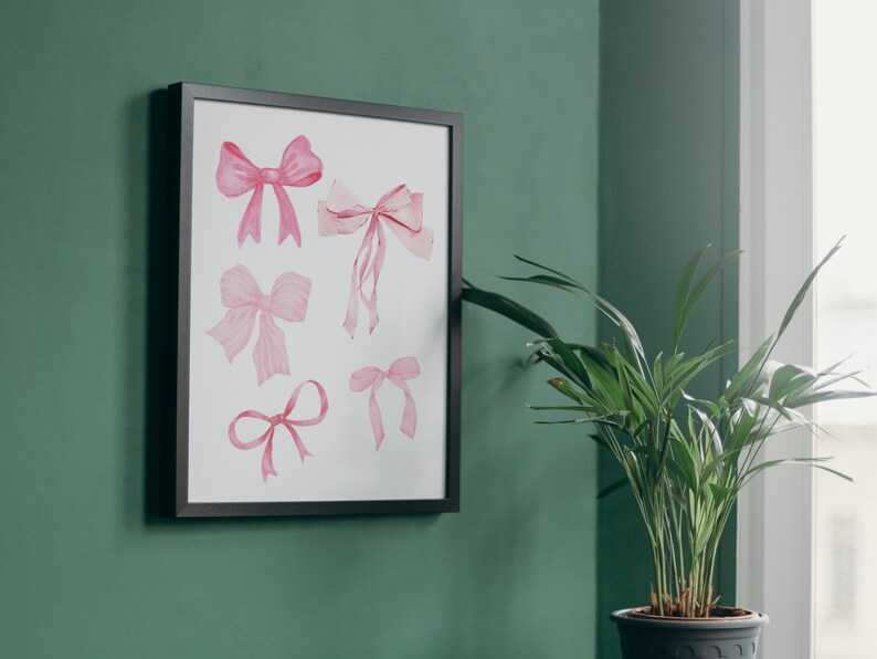May include: A framed print with a white background featuring six pink watercolor bows of various sizes and shapes.